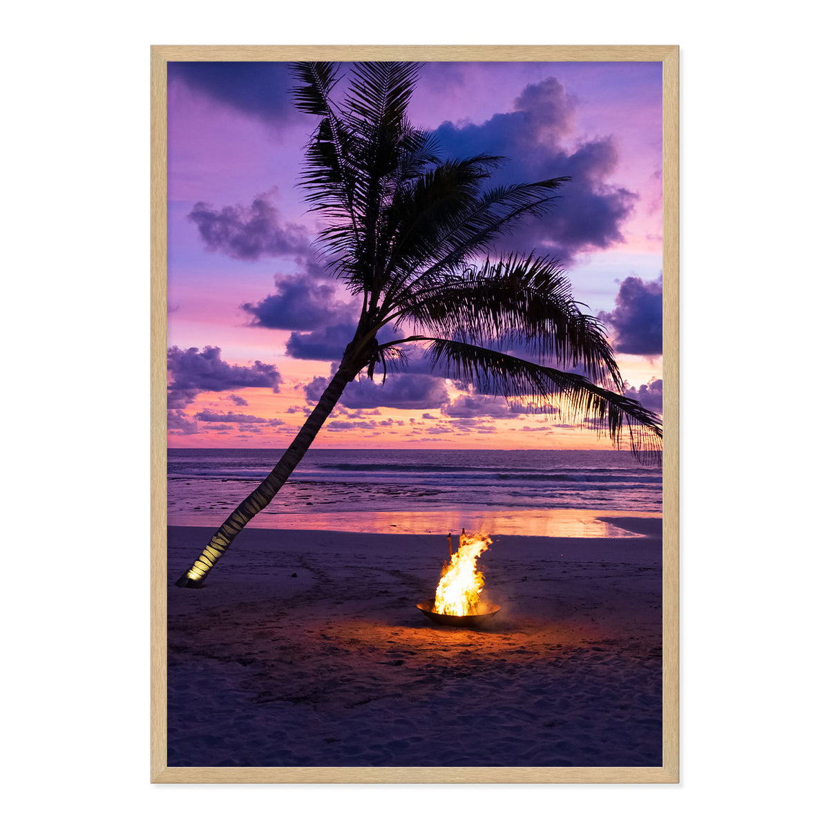 Framed photo of a fire pit by a palm tree on a beach with a sunset sky.