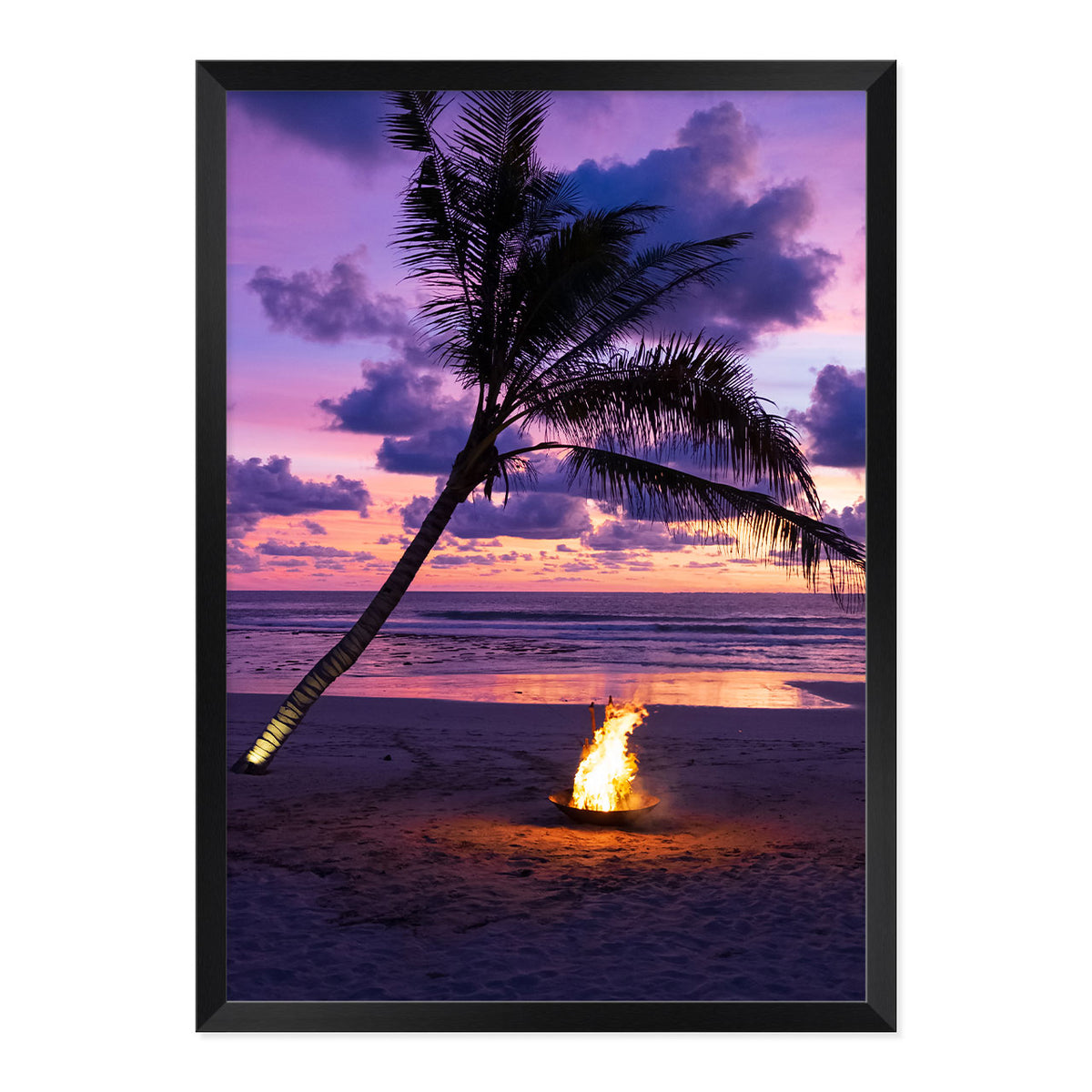 Framed photo of a fire pit by a palm tree on a beach with a sunset sky.