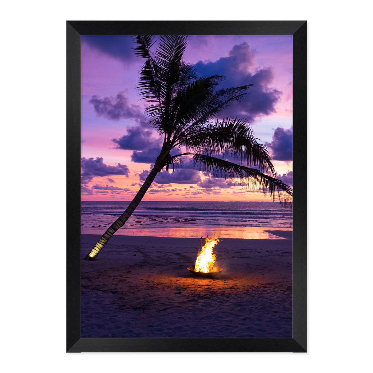 Framed photo of a fire pit by a palm tree on a beach with a sunset sky.