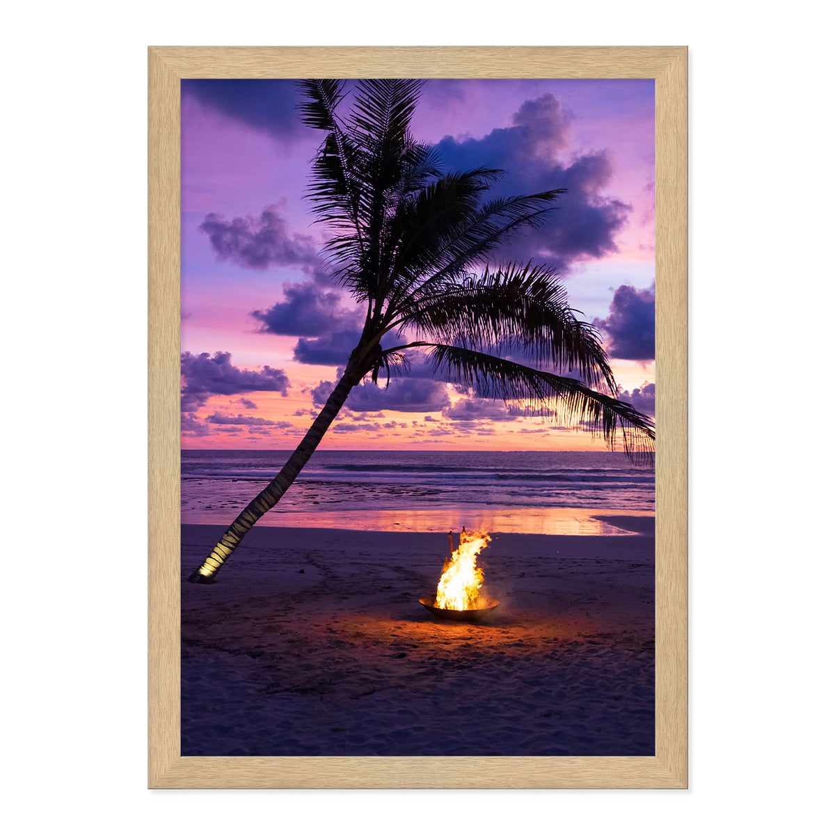 Framed photo of a fire pit by a palm tree on a beach with a sunset sky.