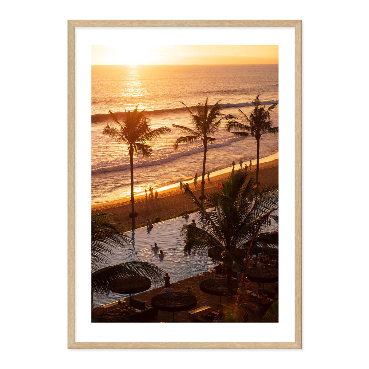 Framed artwork of a sunset over a beach with palm trees and people.