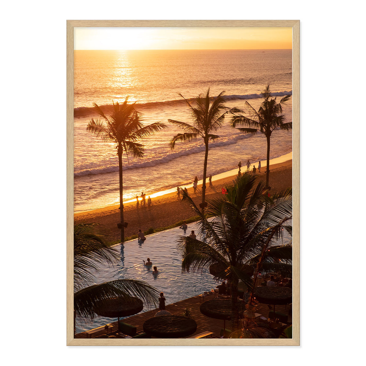 Framed artwork of a sunset over a beach with palm trees and people.