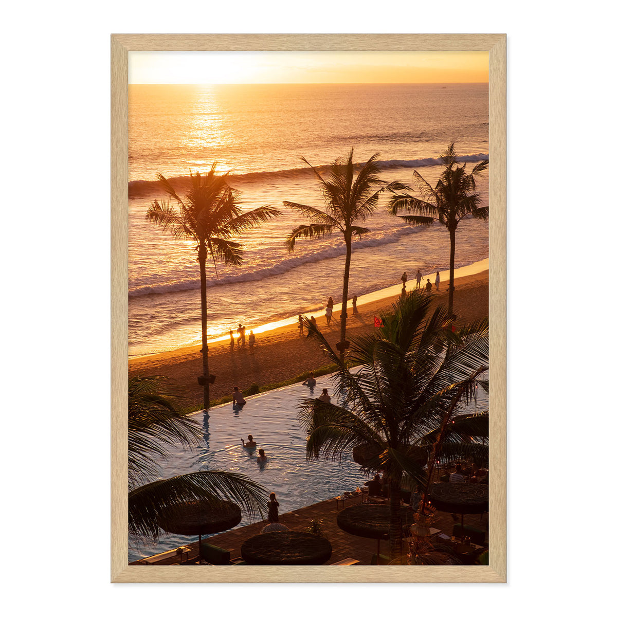 Framed artwork of a sunset over a beach with palm trees and people.