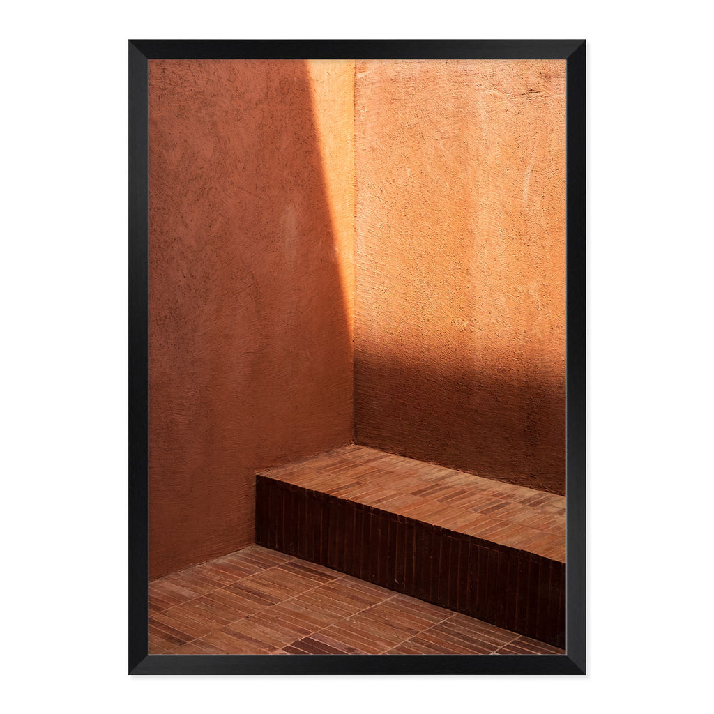 Framed photograph of a textured wall with a bench and shadow